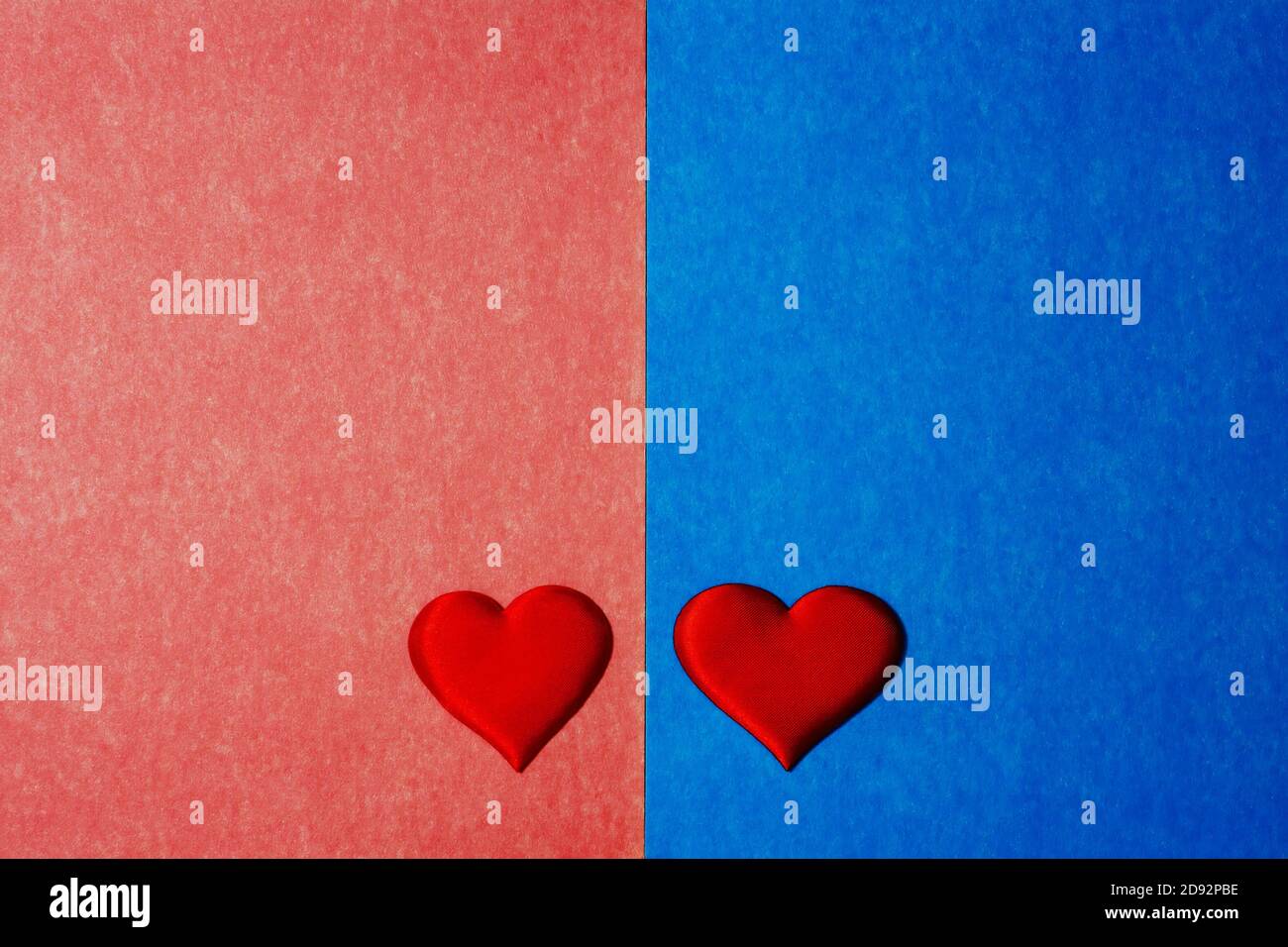 Vue de dessus de deux coeurs rouges sur fond de carton bleu et rose. Espace de copie pour le texte, concept de Saint Valentin. Banque D'Images