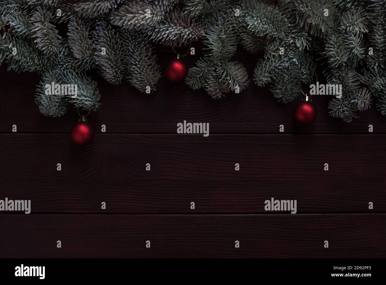 branches d'arbre de noël avec boules rouges sur fond de bois sombre Banque D'Images