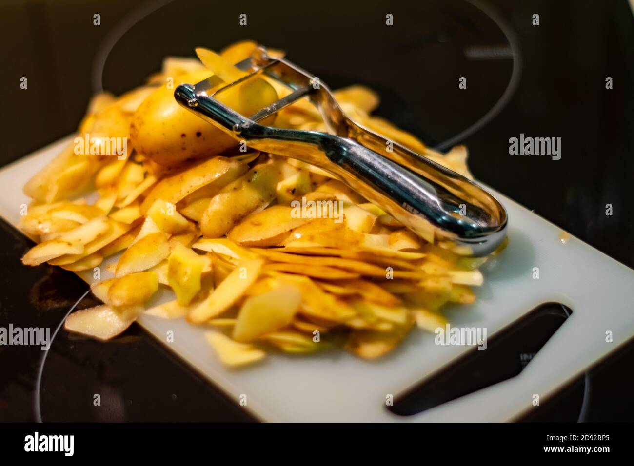 Épluchez les pommes de terre blanches pour la recette du dîner sur le blanc base avec ustensile de cuisine Banque D'Images