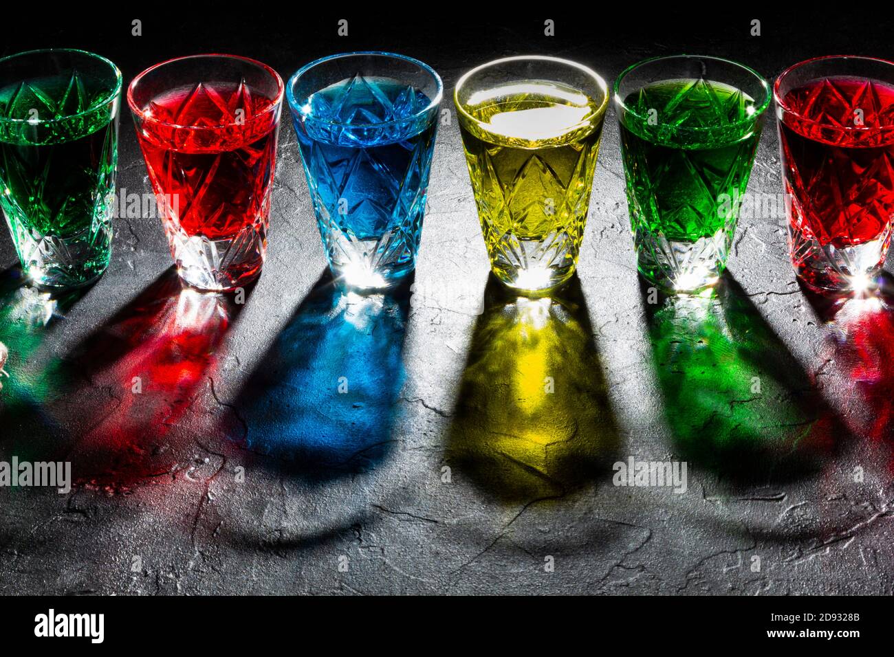 Verres à liqueur multicolores avec alcool fort sur fond sombre Banque D'Images