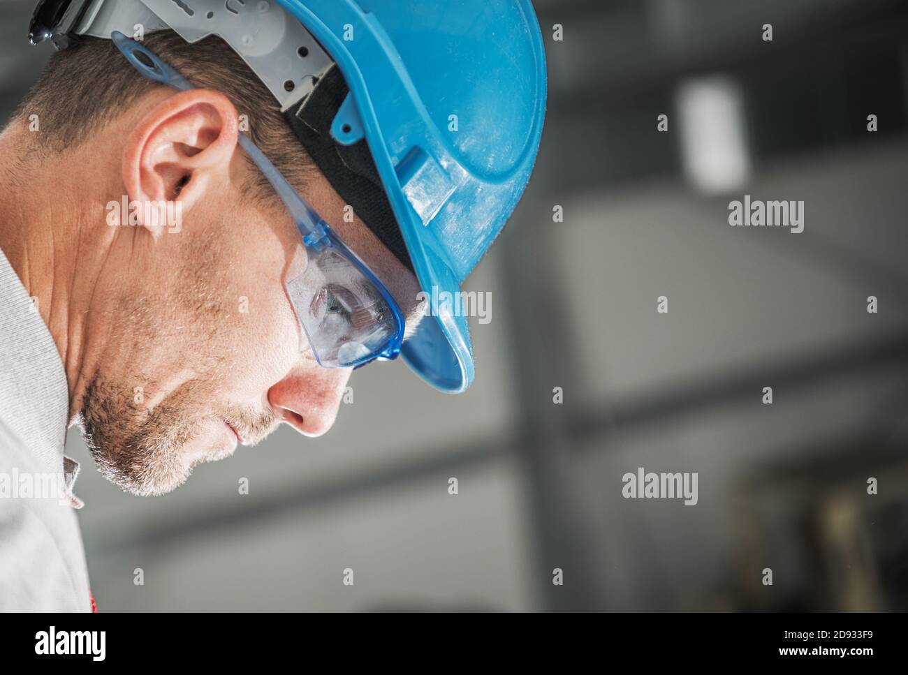 Travailleur de la construction dans ses 40 en Blue casque et yeux lunettes de sécurité profil Portrait. Jour ouvrable. Banque D'Images