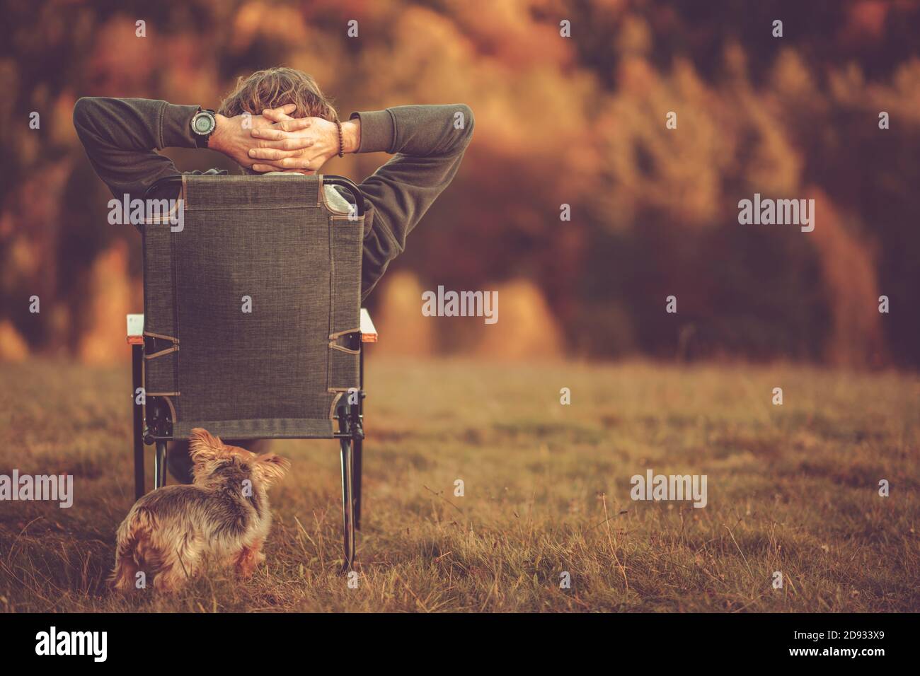 Hommes blancs retraités dans ses années 50 appréciant son stress Free Life dans la nature. S'asseoir quelque part en plein air avec son chien pendant le paysage d'automne. Banque D'Images