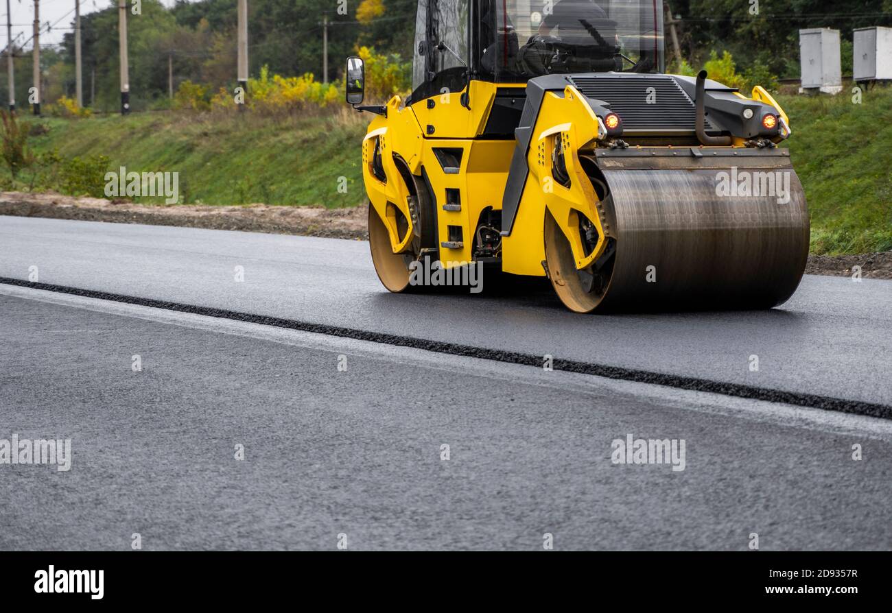 Rouleau de route en asphalte avec compacteur à rouleaux à vibrations lourdes presser l'asphalte chaud neuf sur la chaussée sur un chantier de construction de route. Rouleau à vibrations importantes à Banque D'Images