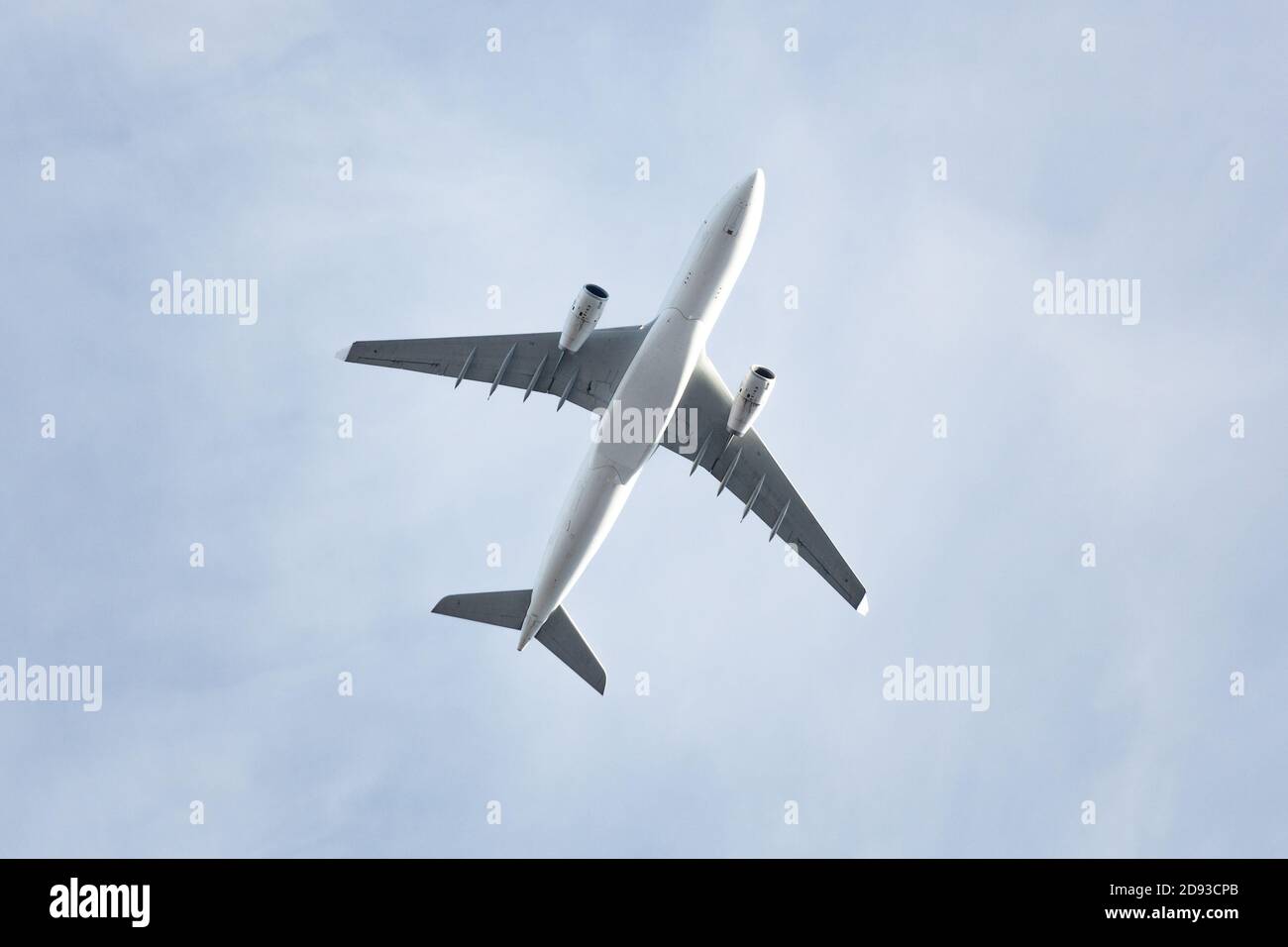 Voyages, transport, aviation. Avion passager volant contre un ciel bleu, vue de dessous Banque D'Images