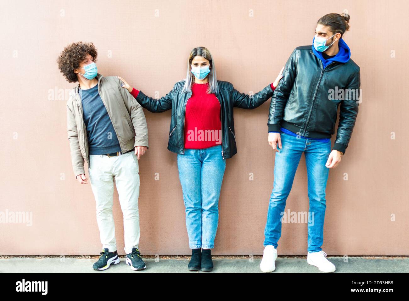 un groupe heureux d'amis portant un masque facial protecteur qui garde les distances sociales après la réouverture du verrouillage. deux hommes et une femme les écartent Banque D'Images