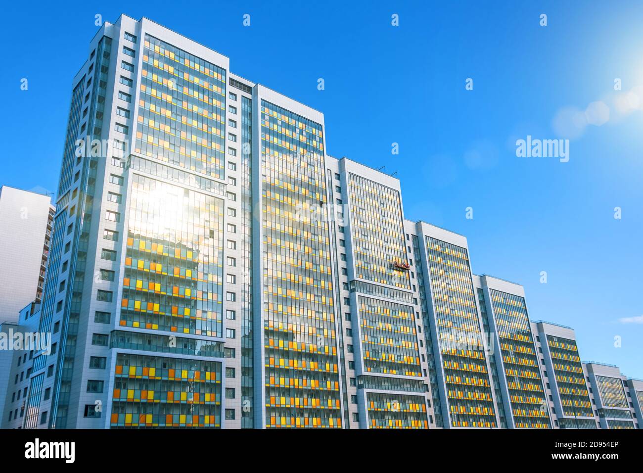 Complexe résidentiel de plusieurs étages avec reflet solaire, et un berceau de construction par les travailleurs pour la finition de la façade extérieure Banque D'Images