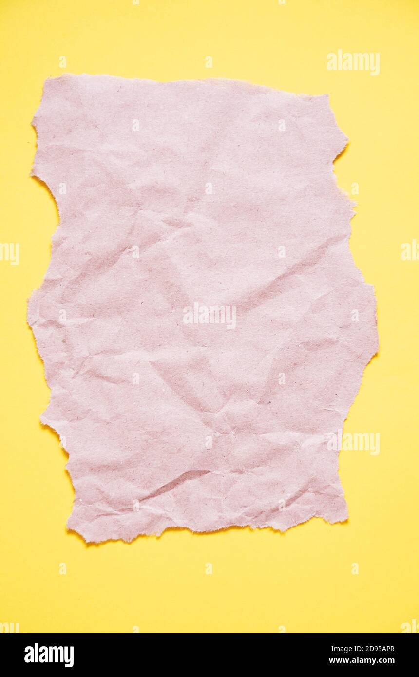 Un morceau de papier d'artisanat avec des bords irréguliers se trouve sur un fond jaune. La vue du dessus. Maquette Banque D'Images