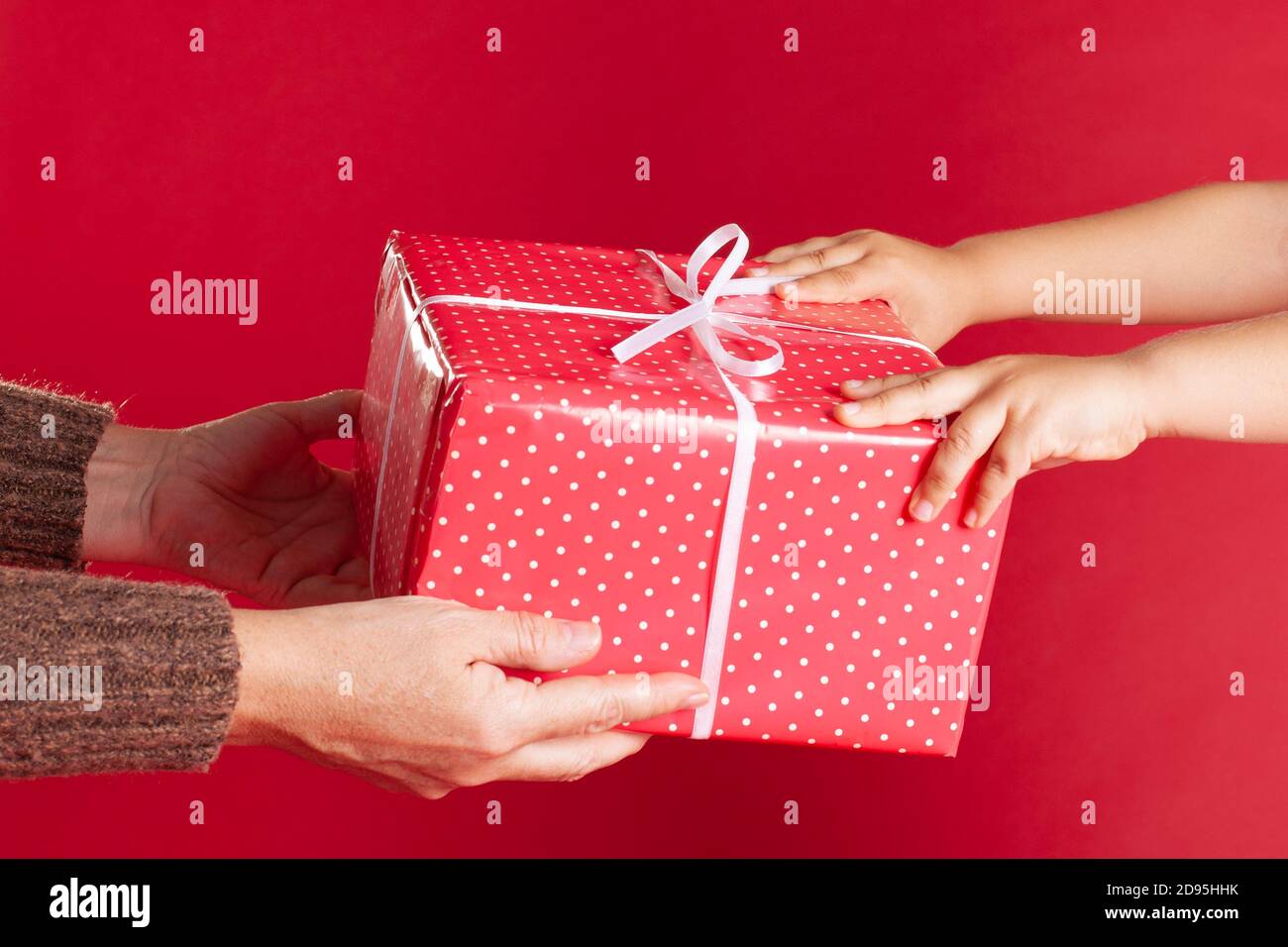 Mains d'un parent donne une belle boîte-cadeau à un enfant, le processus de donner un cadeau pour les vacances à minuit Banque D'Images