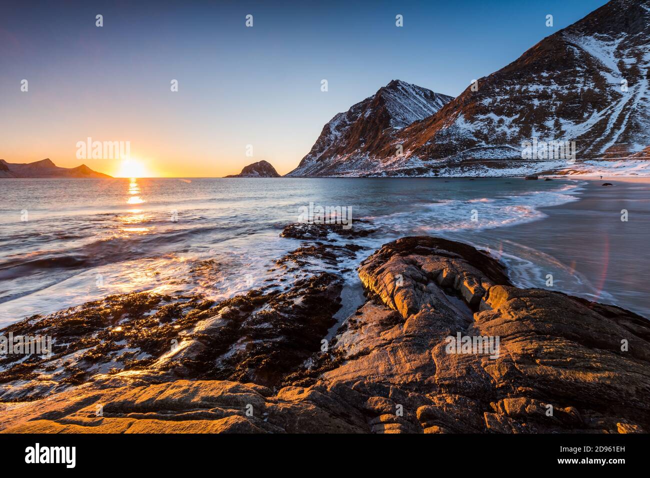 La célèbre plage de sable près de Haukland pendant le coucher du soleil sur le Îles Lofoten en Norvège par temps clair d'hiver avec neige montagnes et ciel bleu Banque D'Images