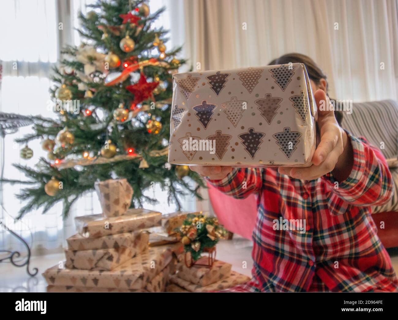 Une jeune fille avec un pyjama de Noël donne à son petit ami un cadeau de noël en un jour de Noël. Photographie d'hiver 2020. Concept arbre de Noël. Banque D'Images