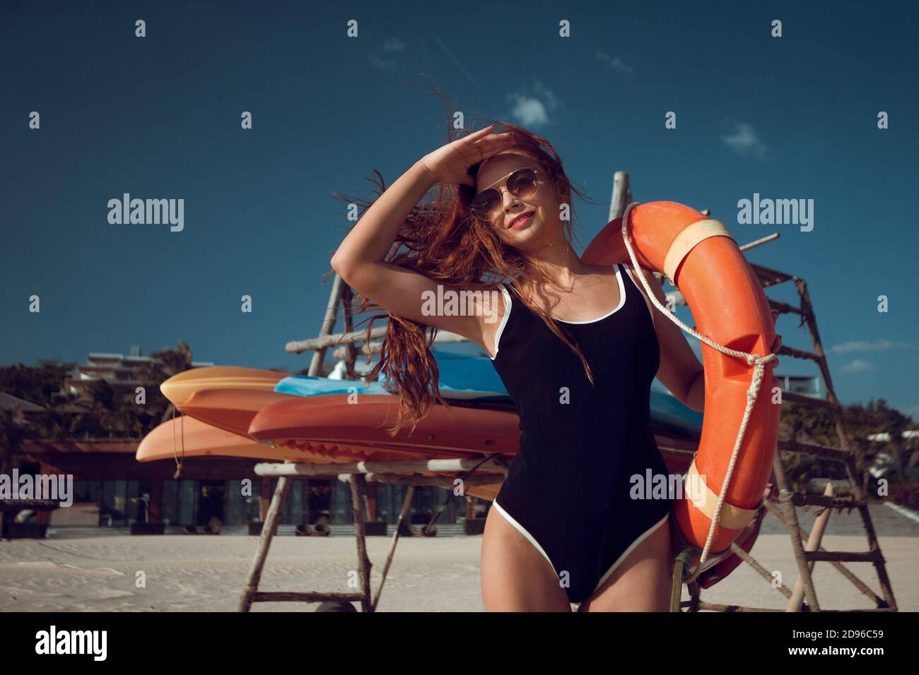 Femme élégante avec bouée de sauvetage sur la plage d'un hôtel tropical. Mode style maritime. Banque D'Images