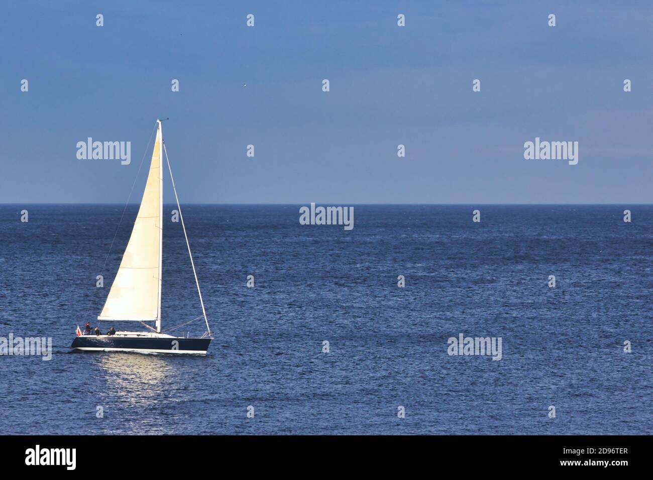 Voilier naviguant sur la mer avec un ciel bleu clair et l'horizon en arrière-plan Banque D'Images