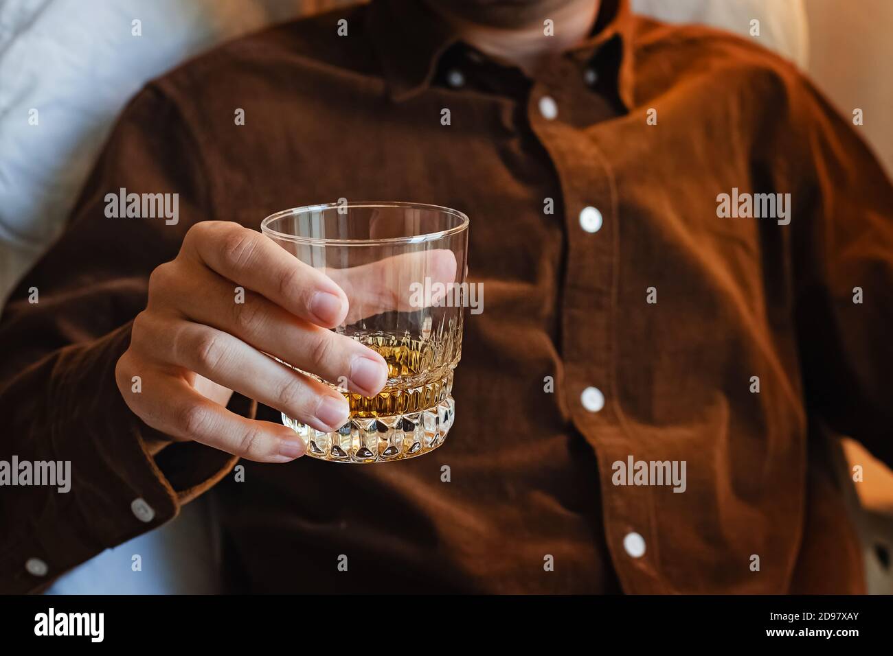 Homme assis sur la chaise et buvant du whisky. Banque D'Images