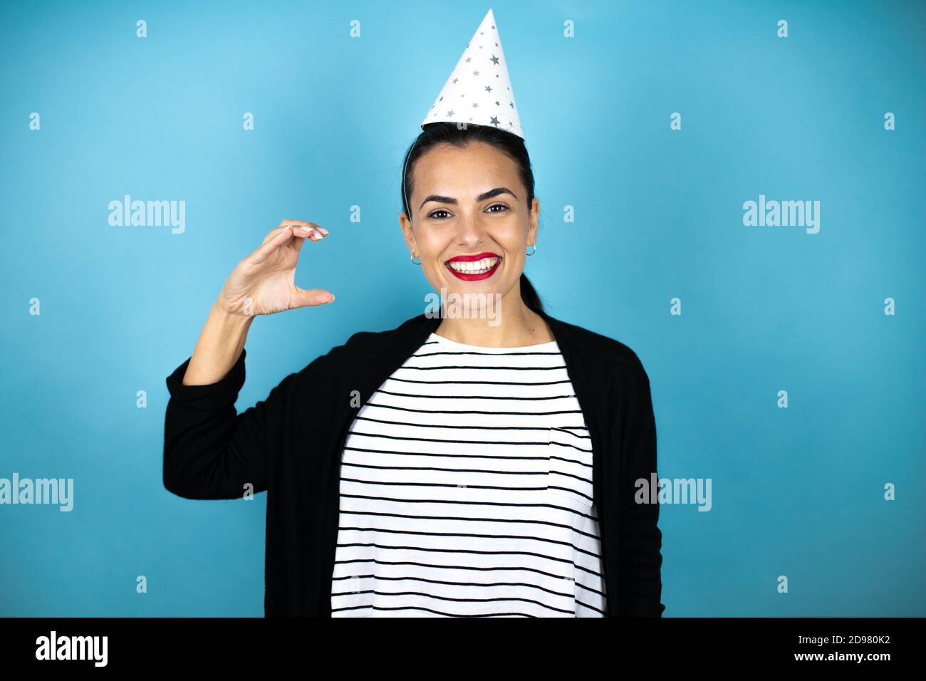 Jeune belle femme portant un chapeau d'anniversaire sur bleu insolé  arrière-plan traite et gestuelle confiante avec la main faisant de petite  taille signe avec le doigt Photo Stock - Alamy