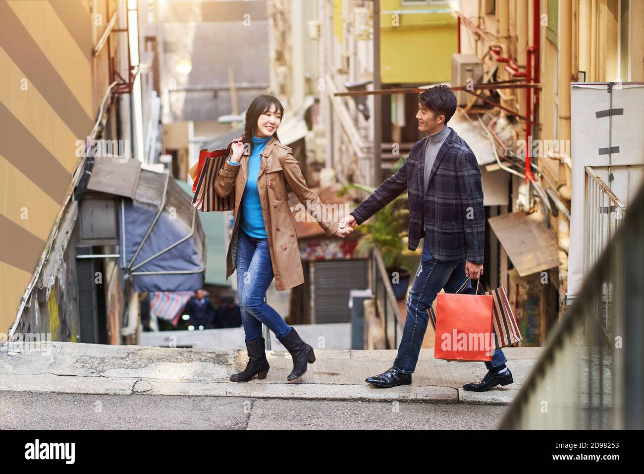 joyeux jeune couple asiatique qui marche dans la rue avec des sacs de shopping en main Banque D'Images