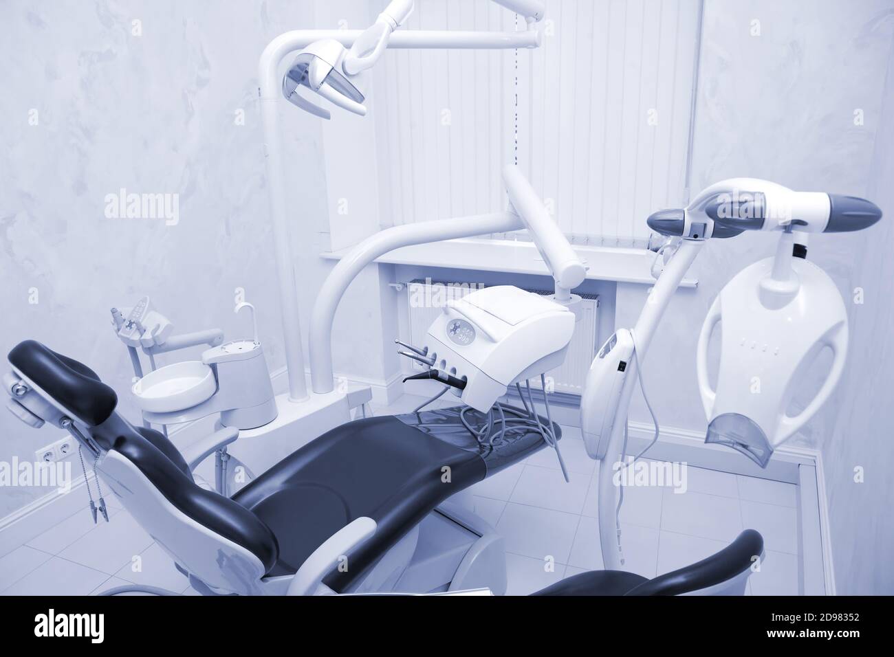 Cabinet dentaire moderne. Chaise dentaire et autres accessoires utilisés par les dentistes en lumière bleue et médique Banque D'Images