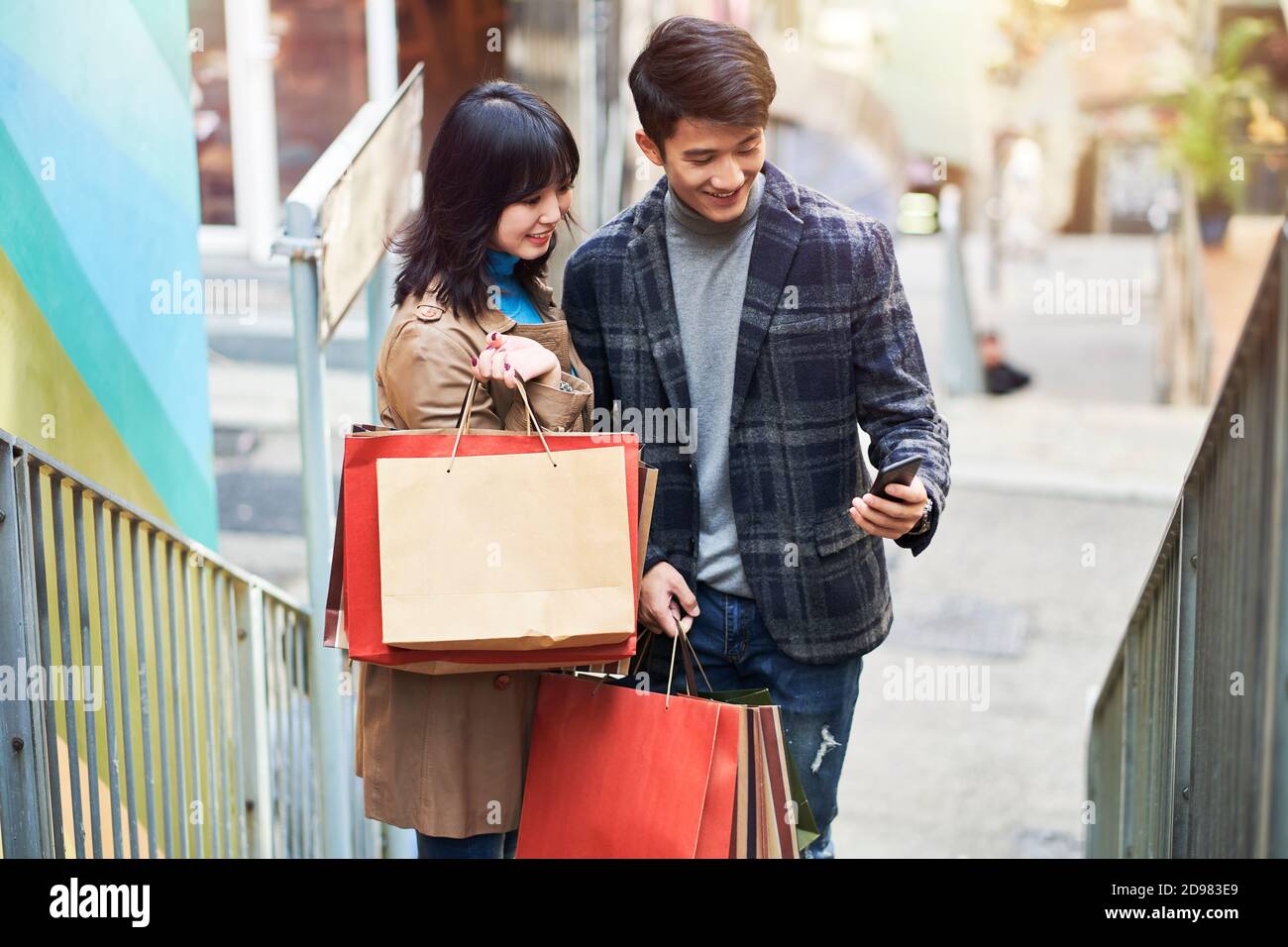joyeux jeune couple asiatique regardant le téléphone portable dans la rue tout en faisant du shopping dans la ville Banque D'Images