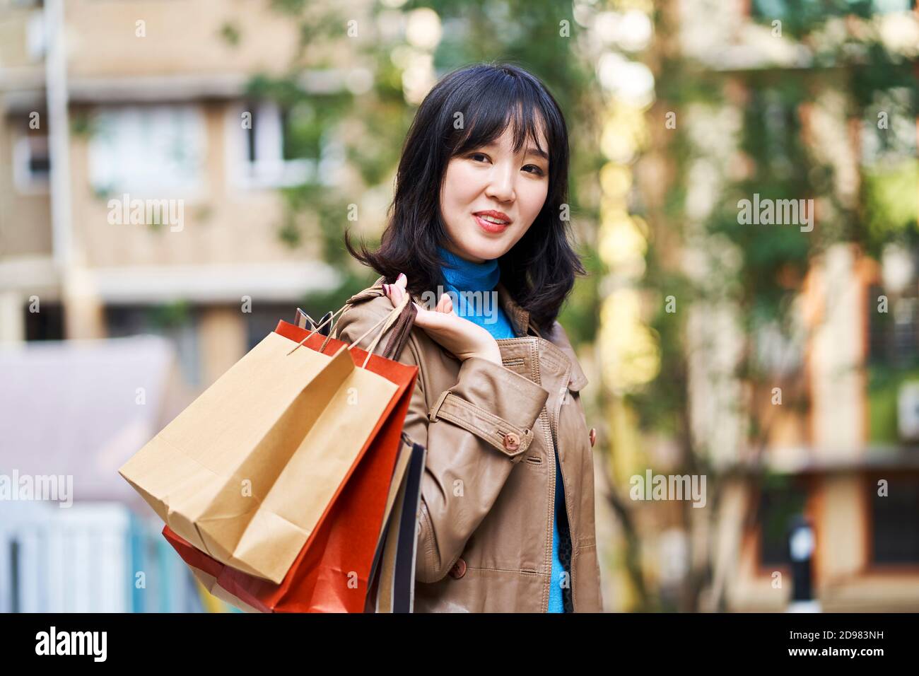 portrait extérieur d'une jeune femme asiatique avec des sacs à provisions en main Banque D'Images