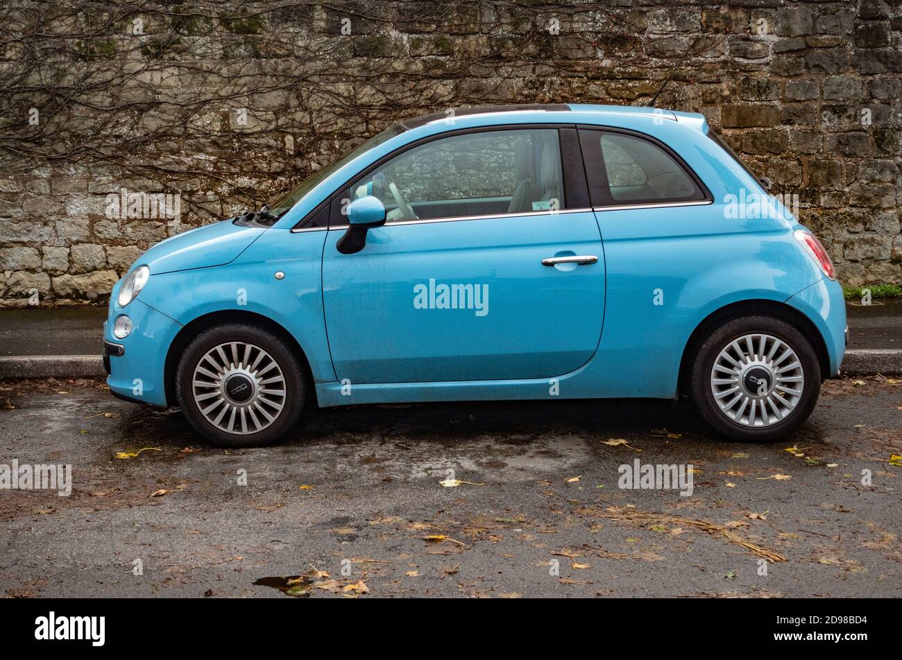 Petite voiture Fiat 500 bleue avec fond de mur en pierre Banque D'Images