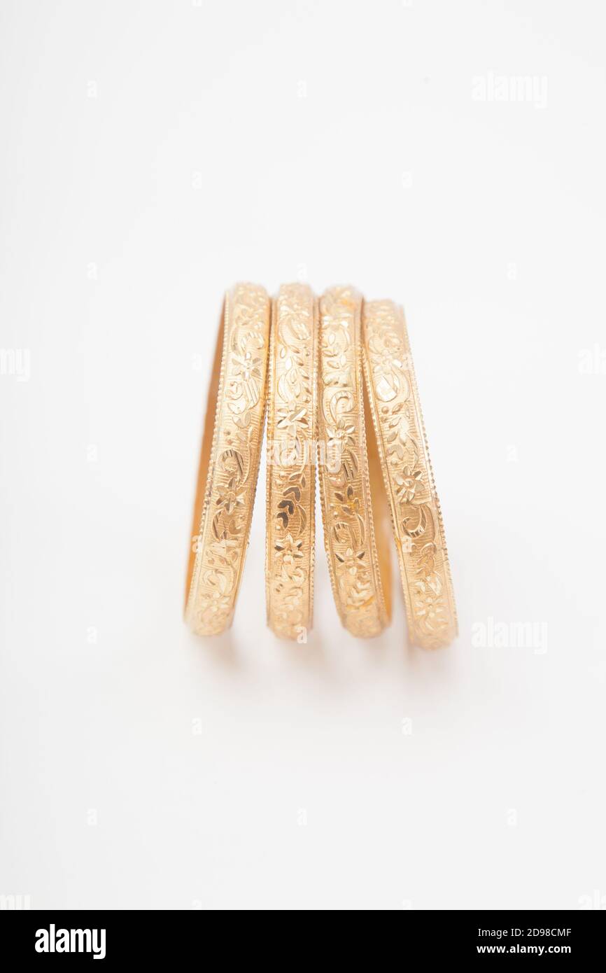 Ensemble vertical de bracelets dorés massifs incrustés sur fond blanc Banque D'Images