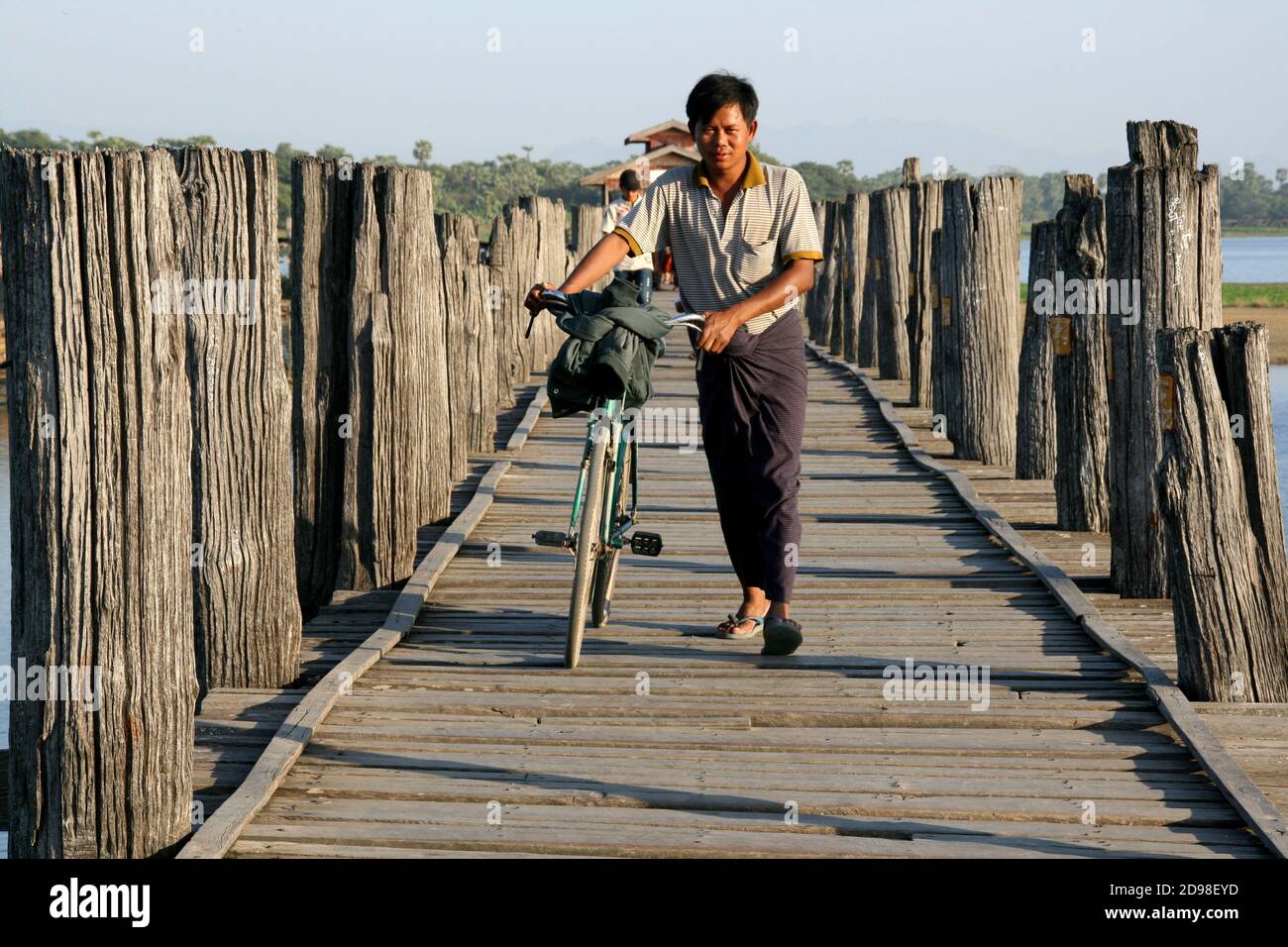 Cycliste traversant le pont U Bein au lever du soleil à Mandalay, au Myanmar. Banque D'Images