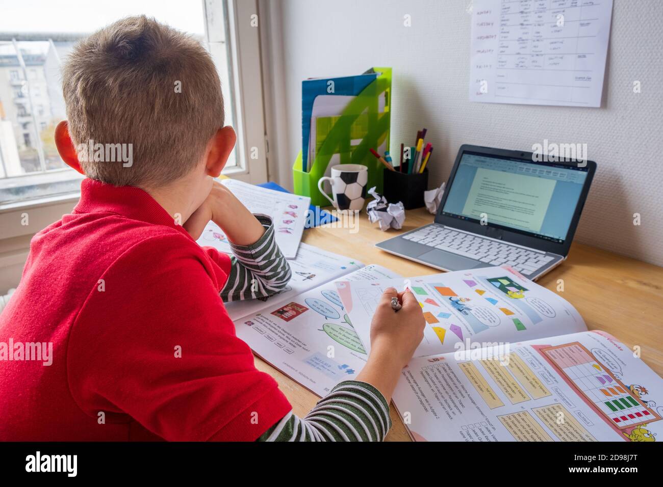 Garçon regardant par la fenêtre tout en homeschooling pendant le verrouillage de corona Banque D'Images