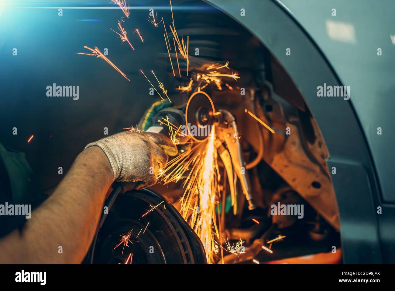 Réparation automobile, travailleur sciant un boulon rouillé avec une scie circulaire, une mouche à étincelles, atelier de réparation automobile. Banque D'Images