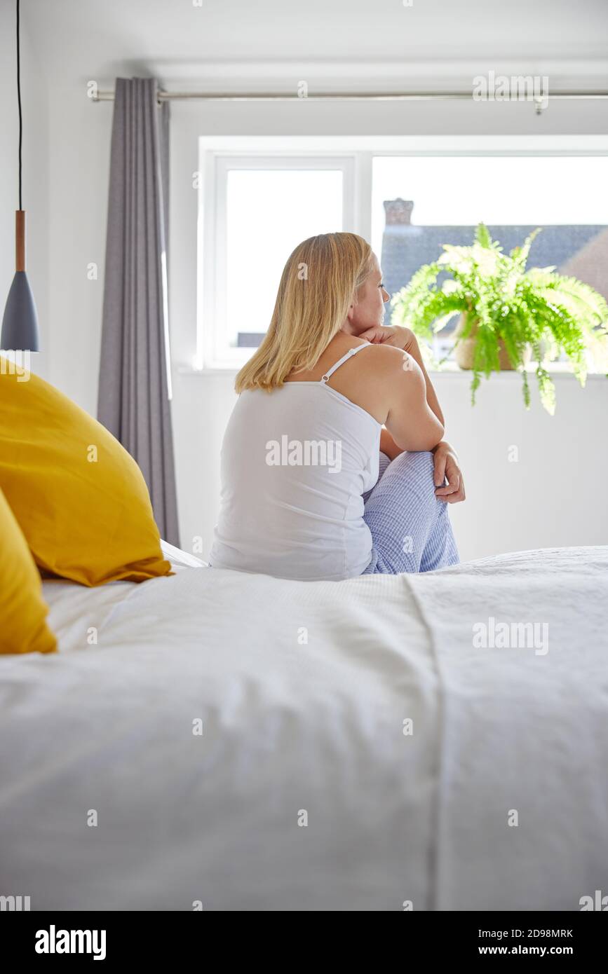 Malheureuse femme d'âge mûr souffrant de dépression assis sur le lit portant Pyjama Banque D'Images
