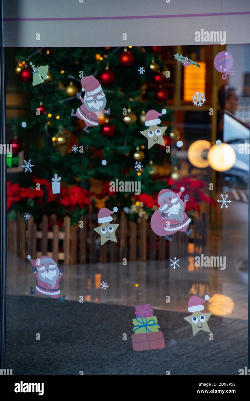 Reflous les reflets dans la fenêtre en verre avec des autocollants de motifs de fête sur une surface transparente avec des lumières et des silhouettes floues. Noël abstrait Banque D'Images