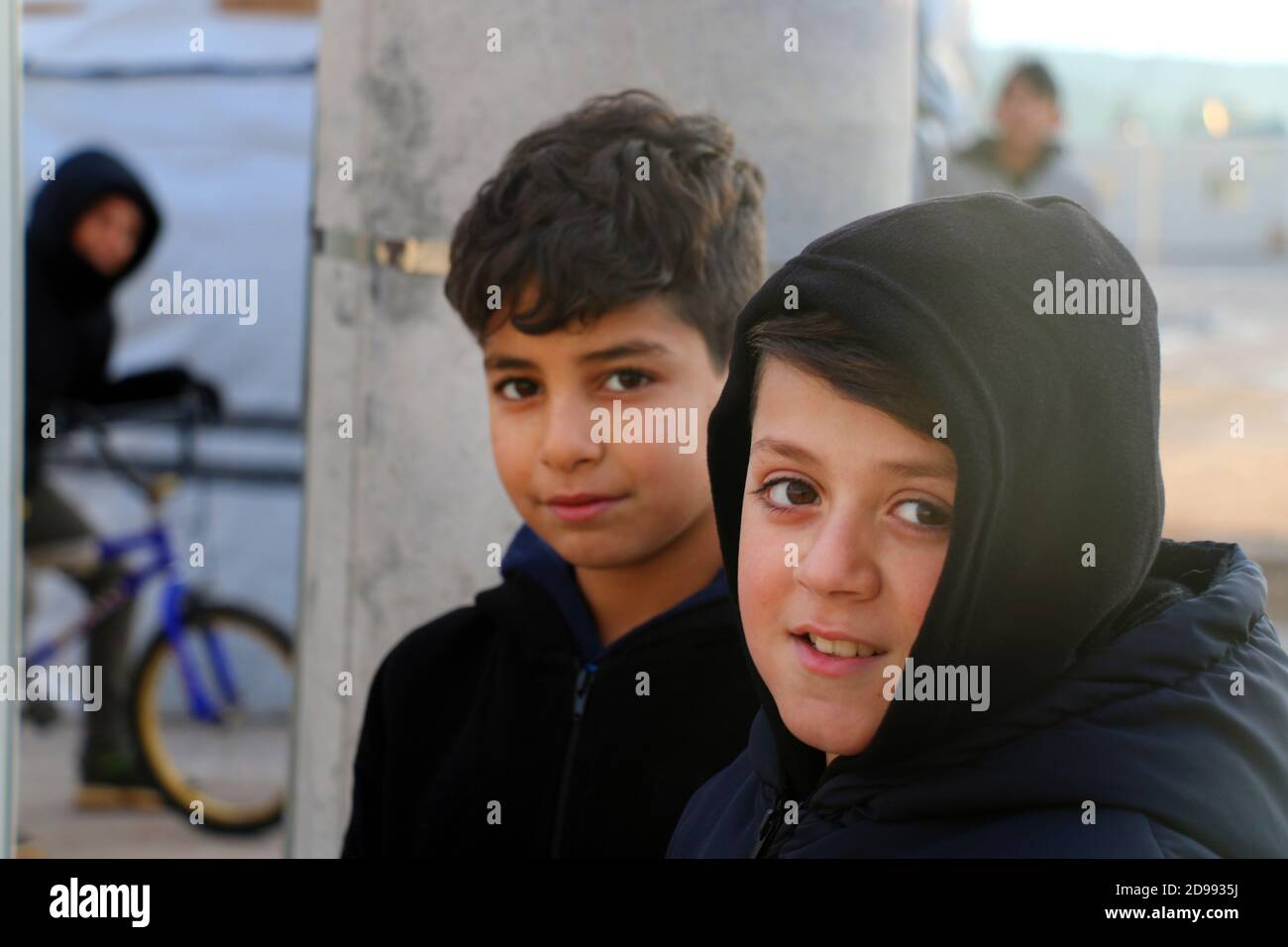 Les enfants regardent avec impatience sans savoir ce que l'avenir réserve. Skaramagas accueille un camp de réfugiés « temporaire », une sorte de salle d'attente où les migrants venant principalement de Syrie, d'Irak et d'Afghanistan restent avant d'être réinstallés ailleurs en Europe. À Skaramagas, ils peuvent également savoir si leur demande de réinstallation a été approuvée ou rejetée. Makariou, Skaramagkas, Grèce. Banque D'Images