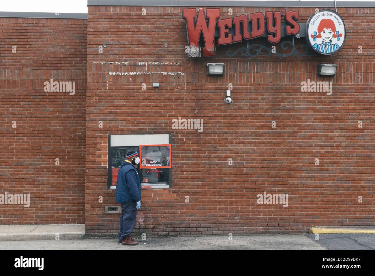 Un homme portant un masque facial attend son ordre en dehors de la chaîne de restauration rapide de Wendy à Woodside, Queens. New York. Banque D'Images