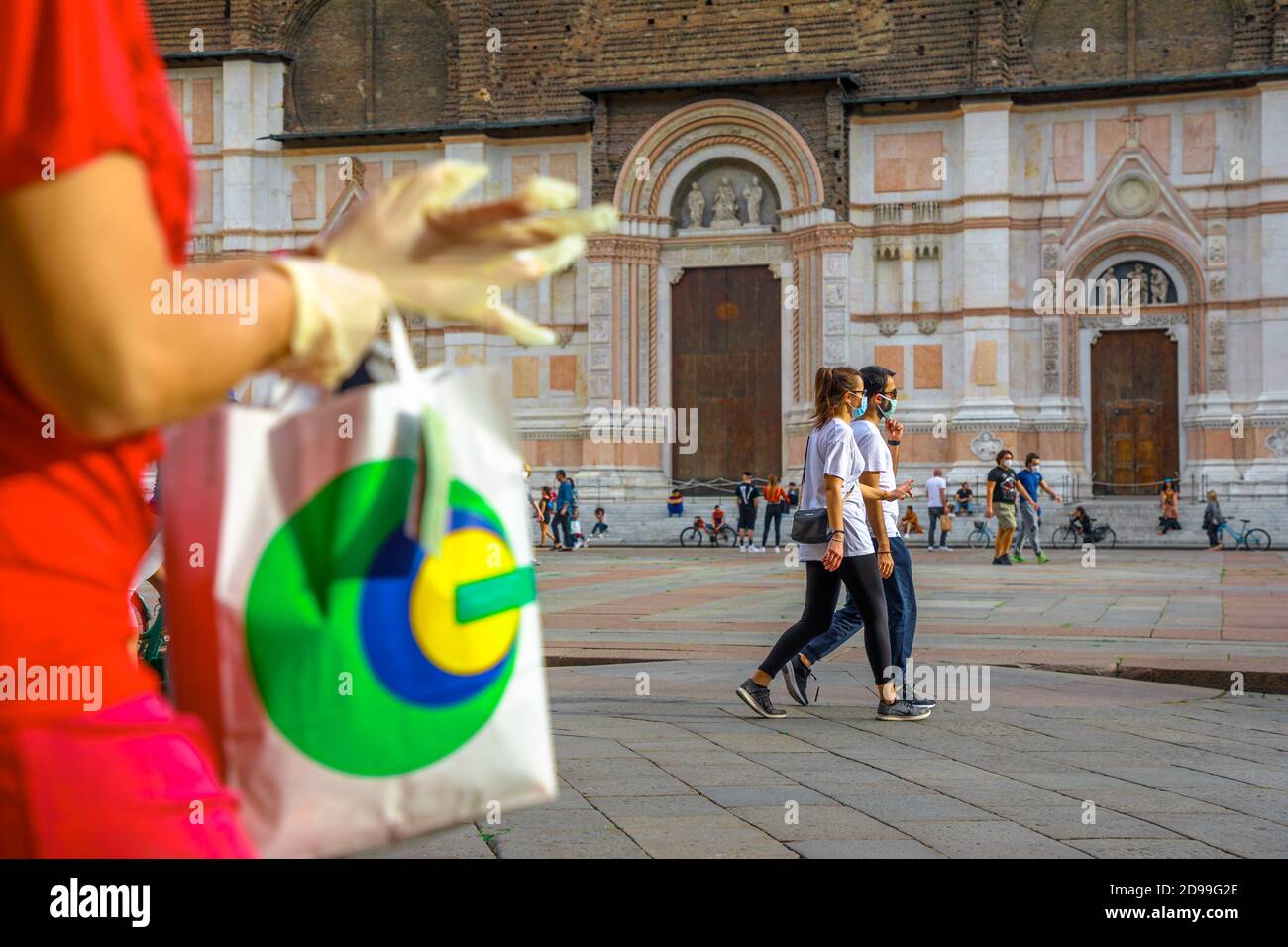 Bologne, Italie - 9 mai 2020 : gants et sac à provisions pour la quarantaine Covid-19 à Bologne. Les personnes portant un masque chirurgical sur la place Piazza Maggiore avec Banque D'Images