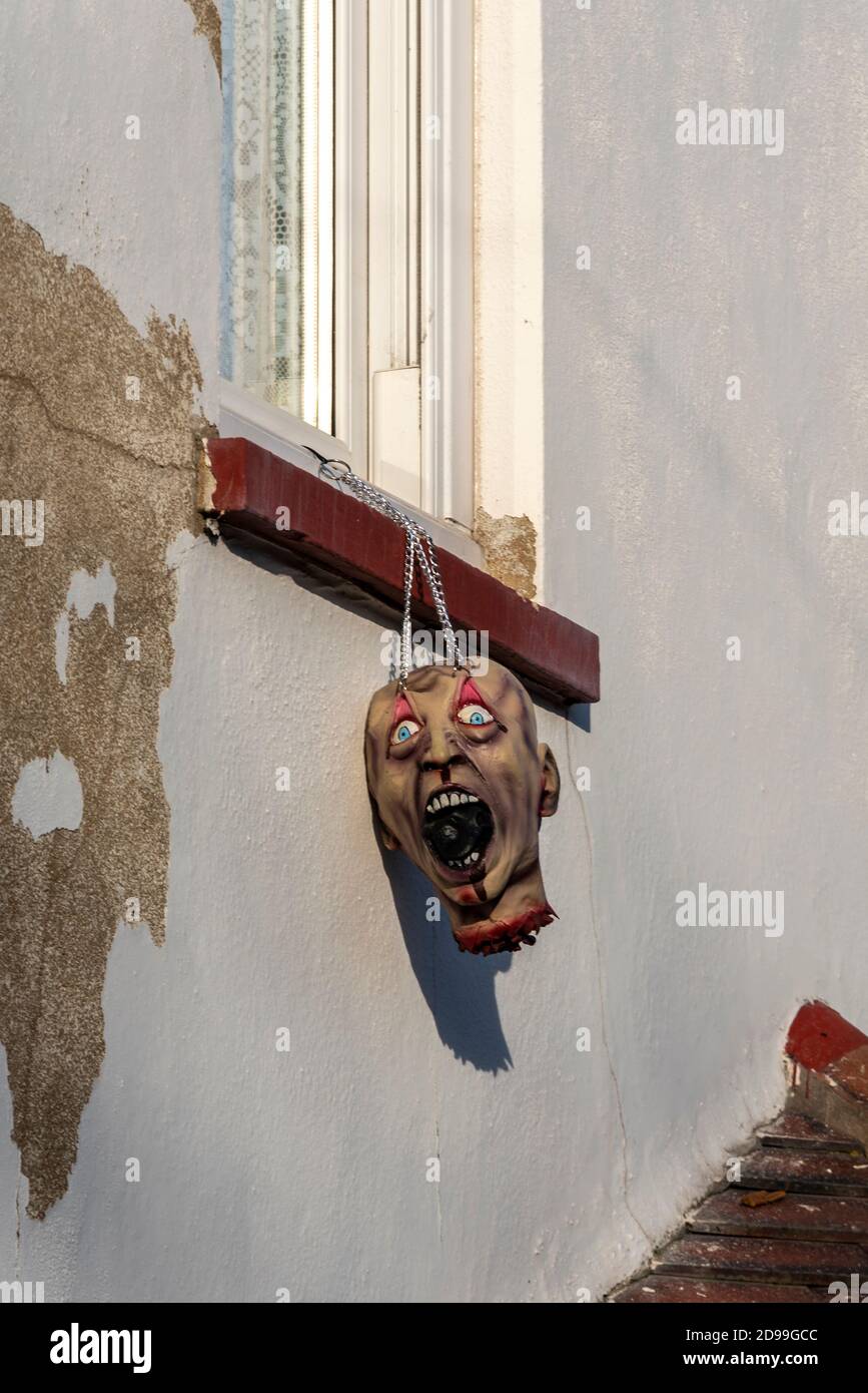 Tête coupée, factice, fausse, suspendue d'une fenêtre à l'étage pour Halloween. Grotesque Banque D'Images