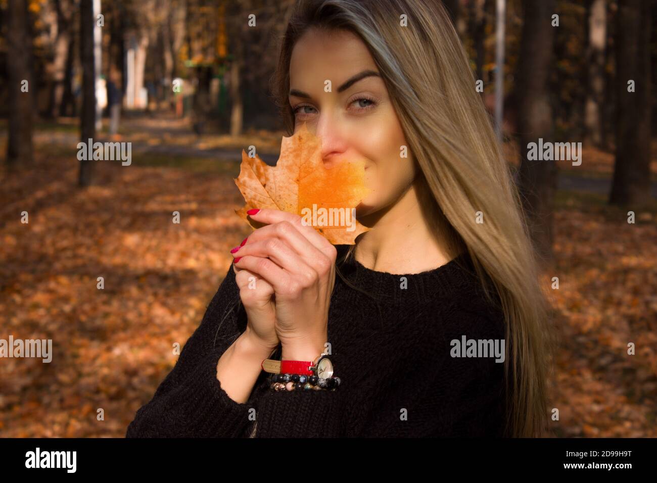 Belle femme heureuse avec le sourire est titulaire d'un automne feuille jaune près de la face Banque D'Images