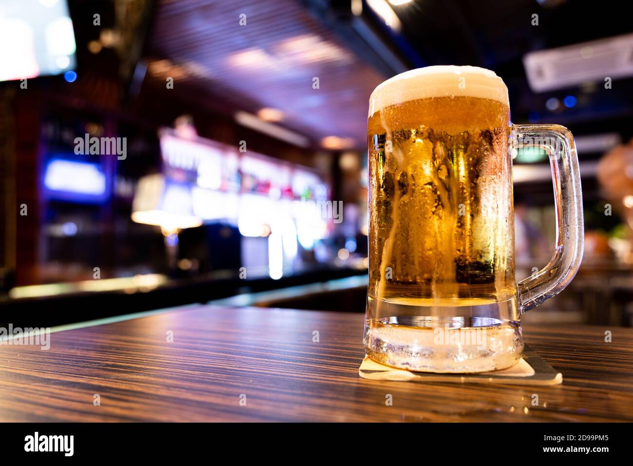 Tasse de bière pression rafraîchissante sur table avec fond de pub Banque D'Images