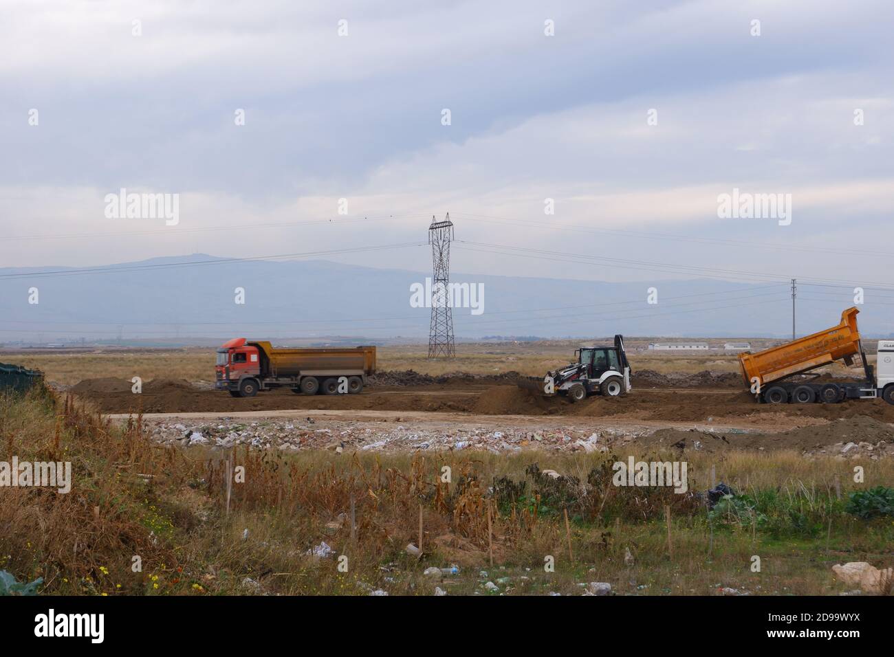 Bouteur et camions travaillant dans les champs par temps nuageux Banque D'Images