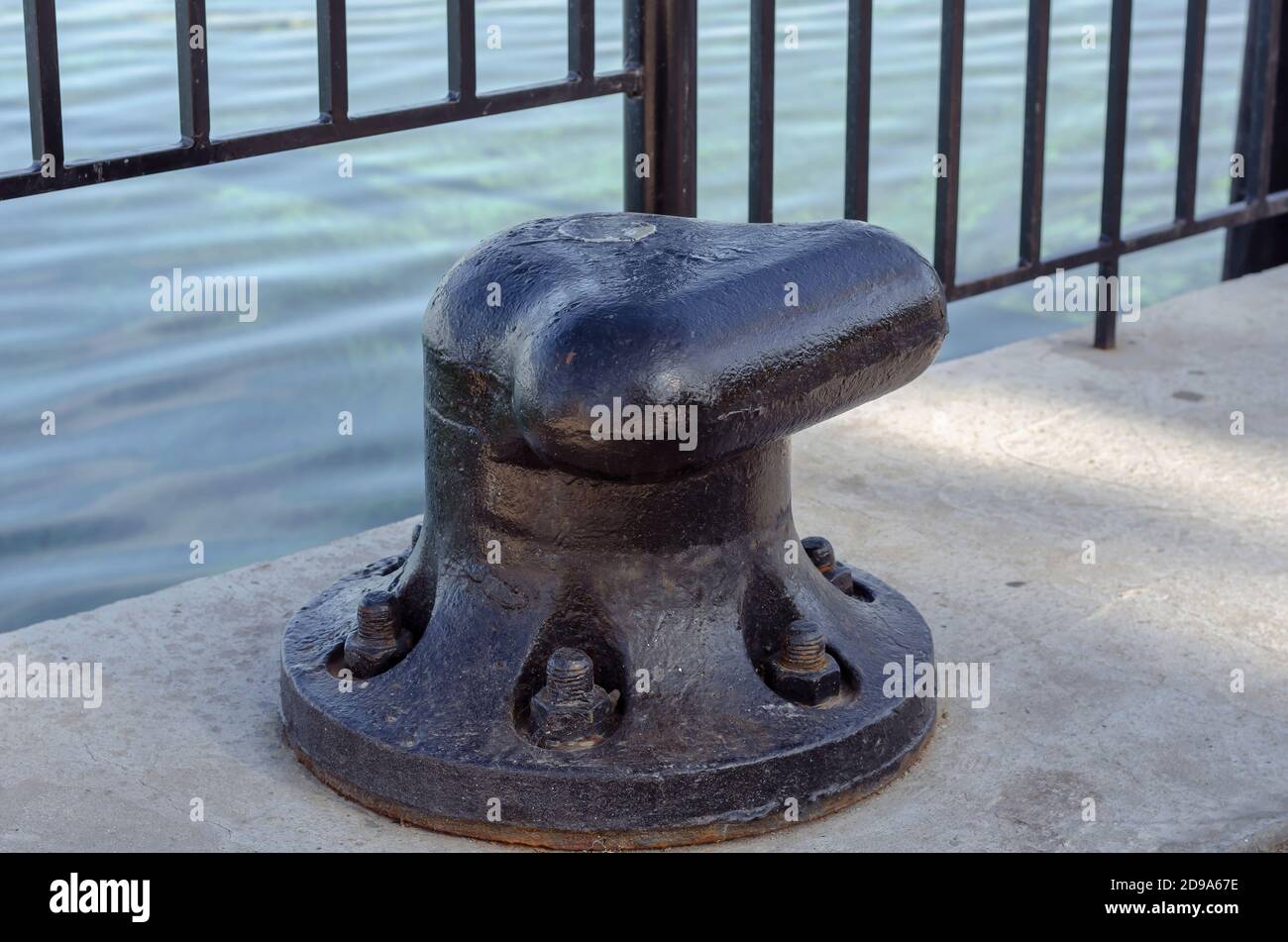 Grand bollard noir sur un quai en béton. Conçu pour la fixation et l'amarrage de gros navires, ferries, bateaux. Gros plan Banque D'Images