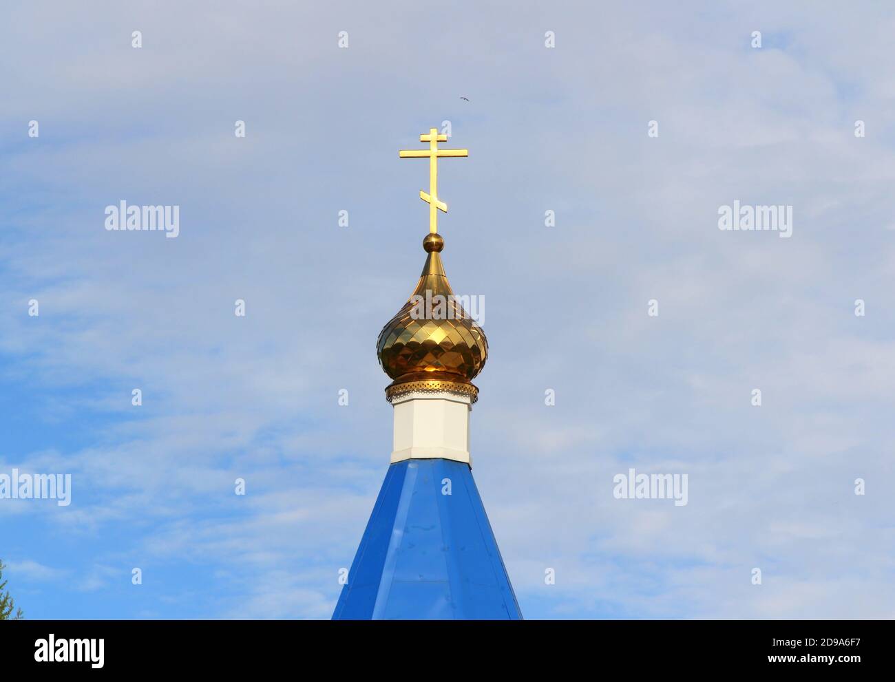 Église chrétienne orthodoxe avec toit bleu, dôme doré et croix en Russie. Un bâtiment pour les cérémonies religieuses avec un clocher contre un ciel nuageux. Banque D'Images