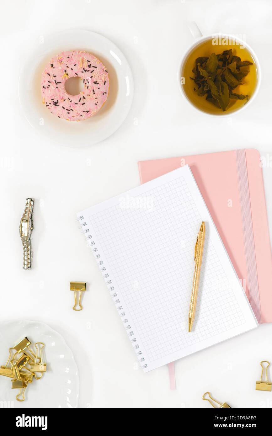 Repose-plat élégant pour blogueur de mode pour femme. Lieu de travail d'un travailleur indépendant ou de bureau: Un Bloc-notes avec une page vierge, un stylo, une tasse de thé vert, un Banque D'Images