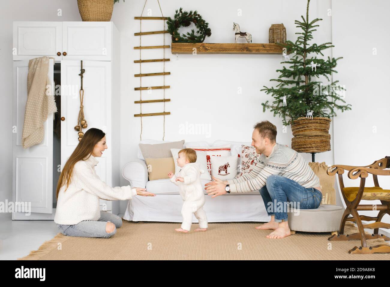 Le thème des vacances en famille est nouvel an et Noël. Jeune famille européenne: Maman, papa, enfant 1 an assis sur le plancher en bois près du CHRI Banque D'Images