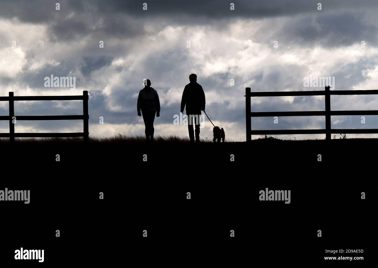 MAM et femme marchant avec un chien en silhouette sur la ligne d'horizon. Banque D'Images