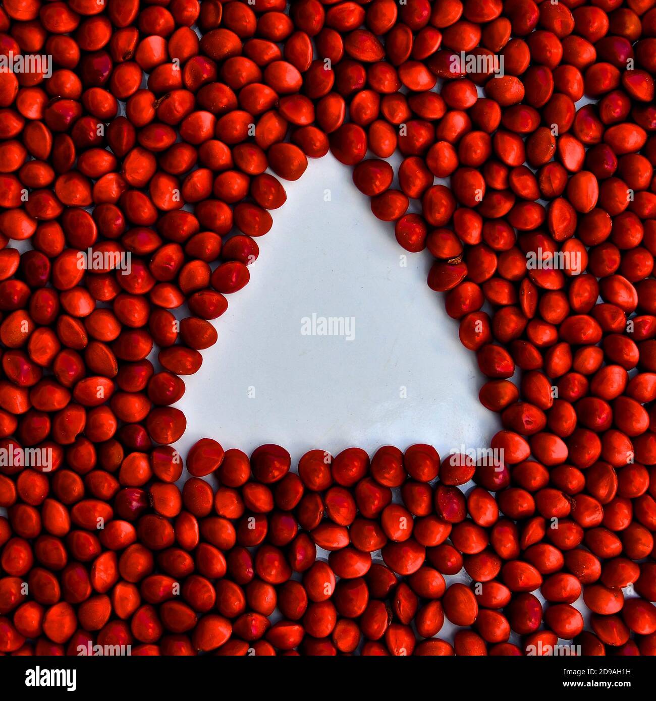 Triangle blanc d'espace négatif créé sur fond de perles rouges brillantes. Banque D'Images