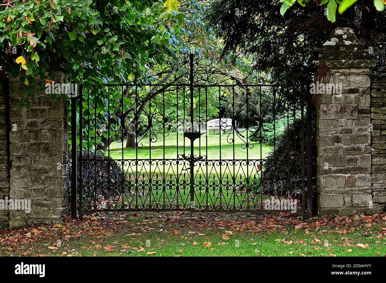 Entrée peu utilisée d'un grand jardin de campagne anglais, avec une clôture en fer forgé très ornée. Banque D'Images
