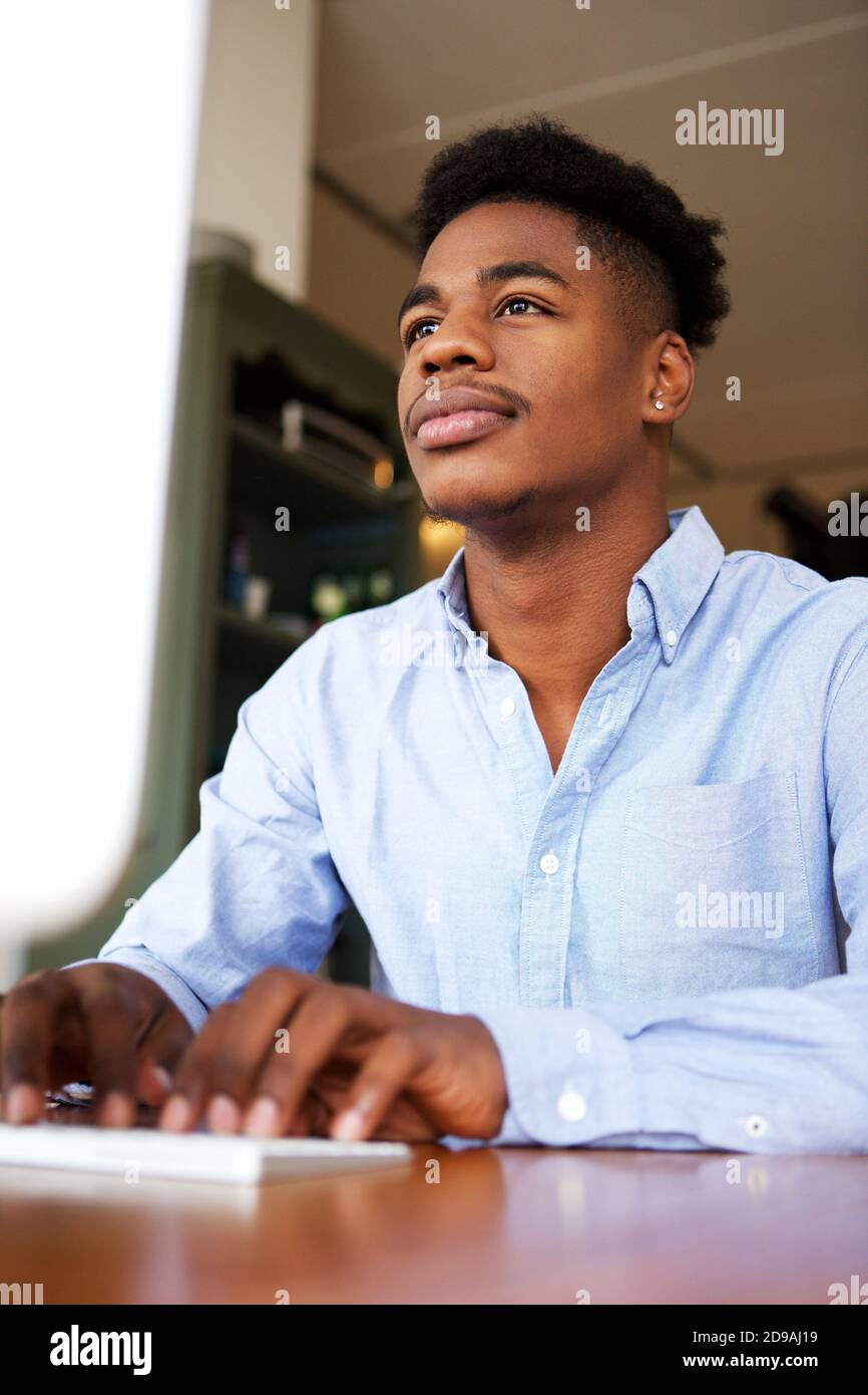 Portrait d'un jeune homme noir travaillant avec un ordinateur au bureau Banque D'Images