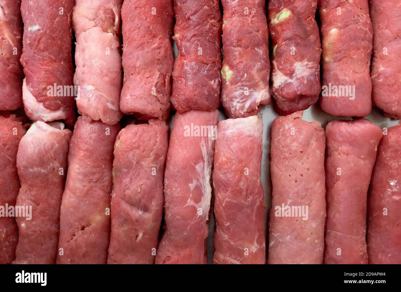 Les blancs de saucisses de viande rondes sont empilés dans une rangée. Cuisson de plats de viande pour le déjeuner. Banque D'Images