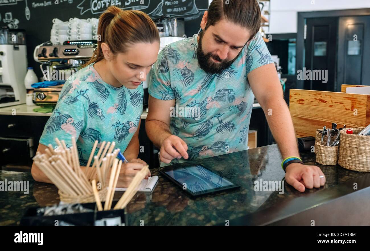 Les propriétaires d'un café travaillant à la recherche de la tablette Banque D'Images