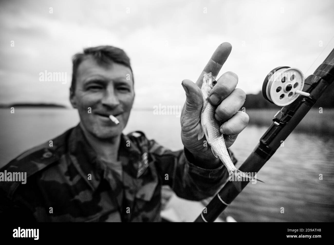 Homme pêche canne sur la rivière sur un bateau en caoutchouc. Photo en noir et blanc. Banque D'Images