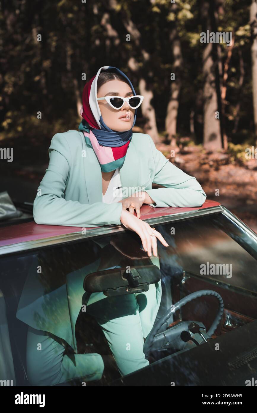 Femme élégante en lunettes de soleil et foulard à l'écart du vintage voiture  sans toit Photo Stock - Alamy