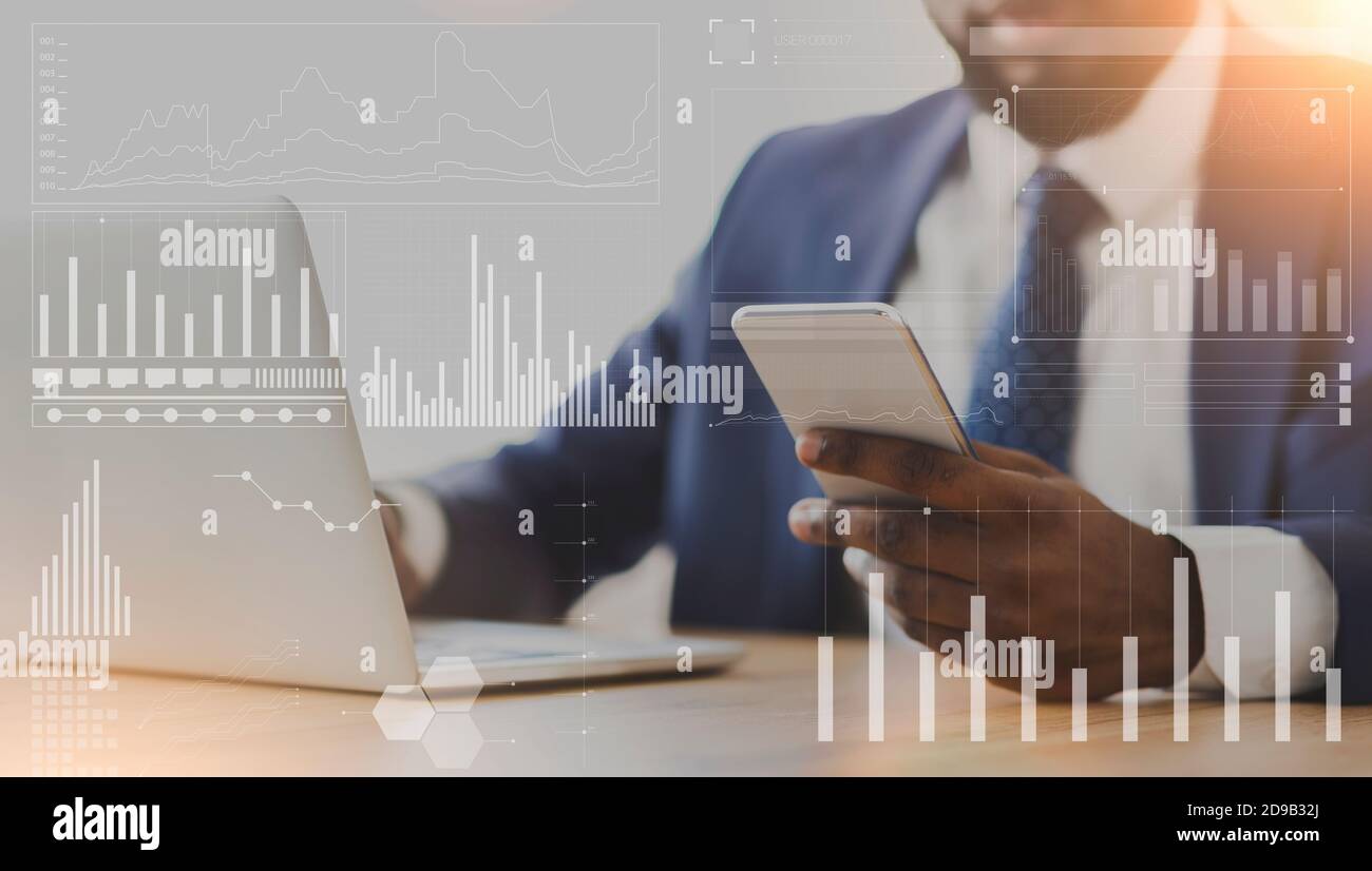 Homme d'affaires afro-américain utilisant un téléphone portable et un ordinateur portable sur le lieu de travail, collage avec des analyses de l'entreprise sur un écran imaginaire Banque D'Images