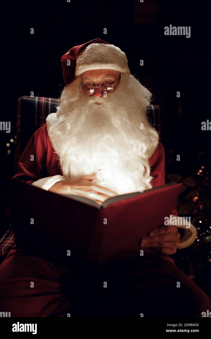 Le Père noël lisant un livre magique dans une pièce sombre Photo Stock -  Alamy